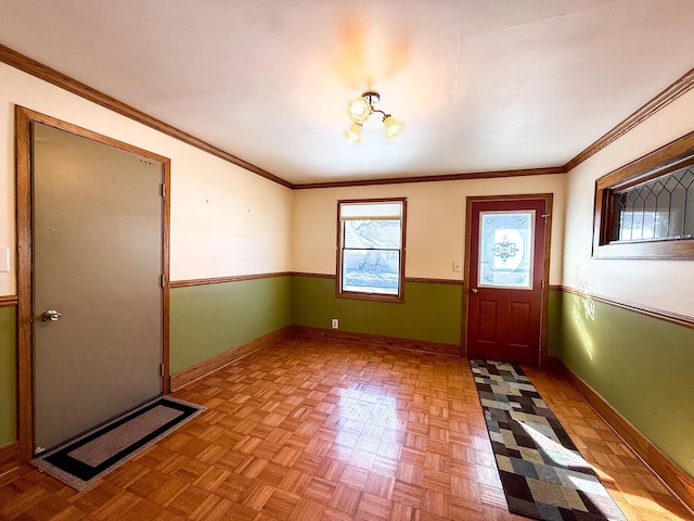 foyer with crown molding, baseboards, and wainscoting