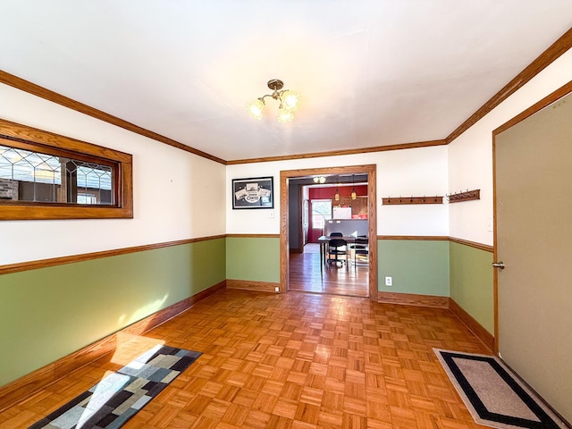 spare room with crown molding, a notable chandelier, and baseboards