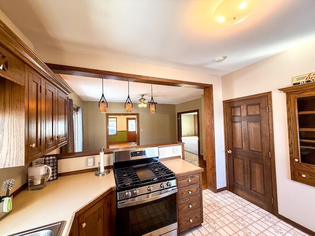 kitchen featuring baseboards, gas range, light countertops, a peninsula, and hanging light fixtures