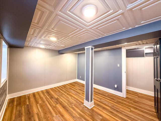 finished below grade area with baseboards, an ornate ceiling, and wood finished floors