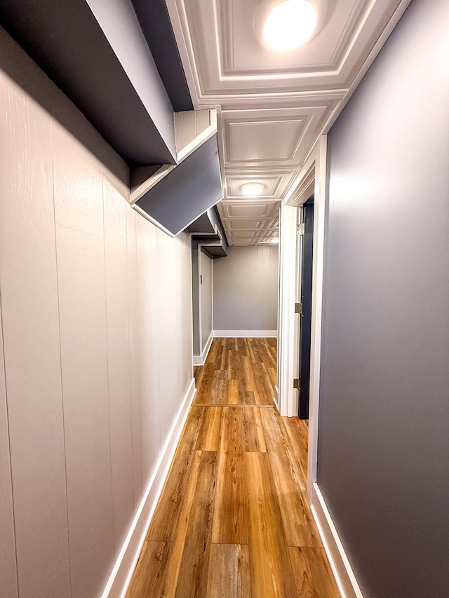 corridor featuring baseboards and wood finished floors