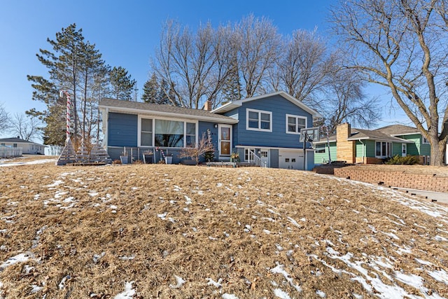 tri-level home with a garage and a chimney