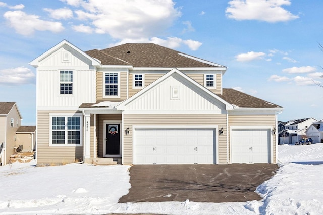 view of front of property with board and batten siding, roof with shingles, an attached garage, and aphalt driveway