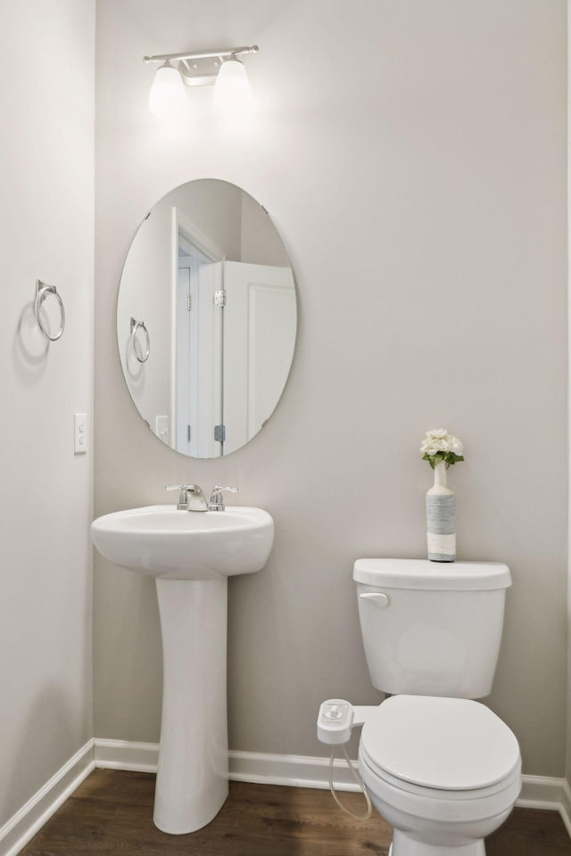 bathroom with toilet, baseboards, and wood finished floors