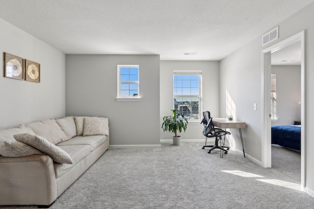 living area featuring a textured ceiling, baseboards, visible vents, and light colored carpet