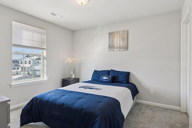 bedroom with baseboards, visible vents, and light colored carpet