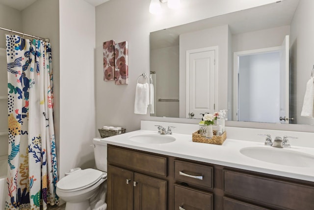 bathroom featuring double vanity, toilet, and a sink