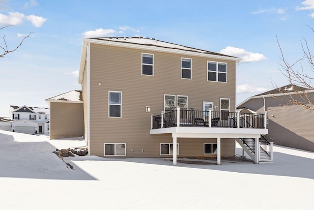 snow covered house with stairway and a wooden deck