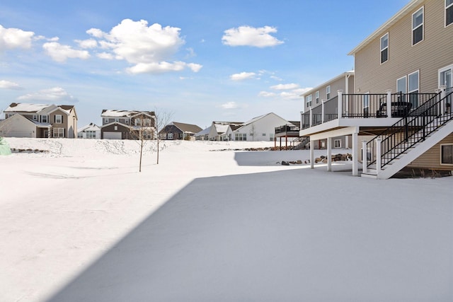 snowy yard with a residential view, a wooden deck, and stairs