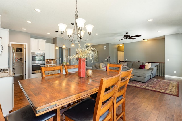 dining space featuring sink, dark hardwood / wood-style floors, and ceiling fan with notable chandelier