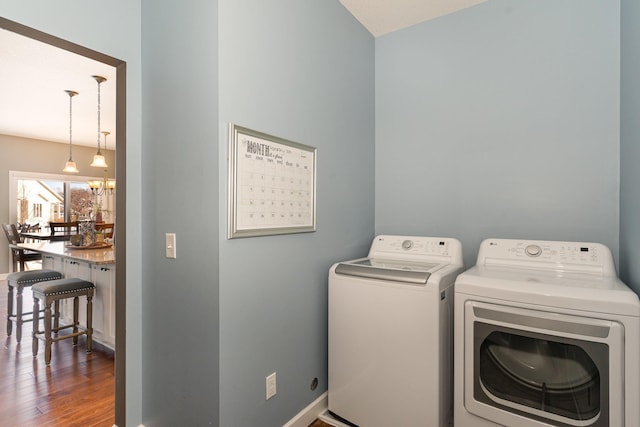 washroom featuring independent washer and dryer, an inviting chandelier, and dark wood-type flooring