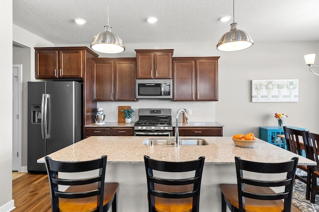 kitchen featuring pendant lighting, stainless steel appliances, backsplash, and sink