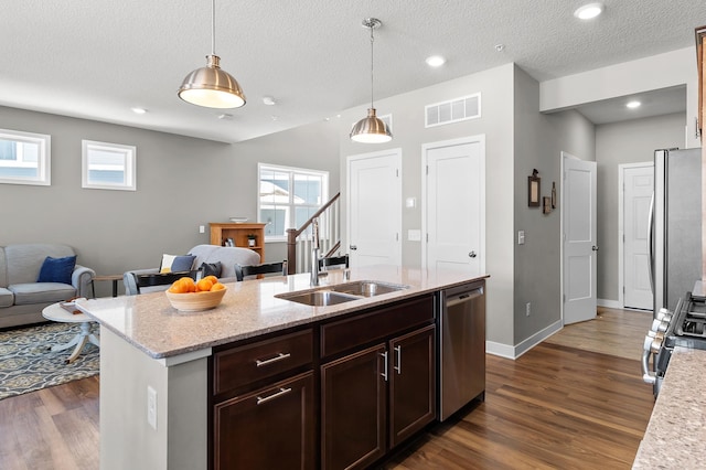 kitchen featuring dark hardwood / wood-style flooring, sink, stainless steel appliances, and pendant lighting