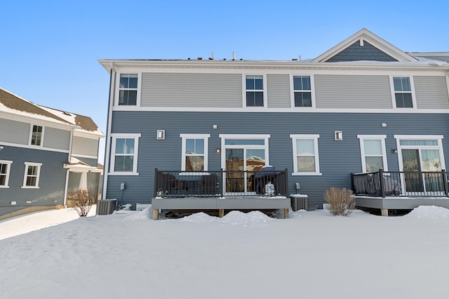 snow covered rear of property featuring central air condition unit and a wooden deck