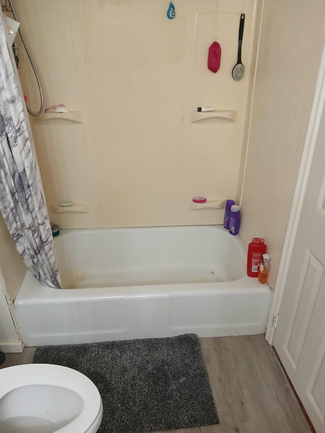 bathroom with shower / bathtub combination with curtain, toilet, and wood finished floors