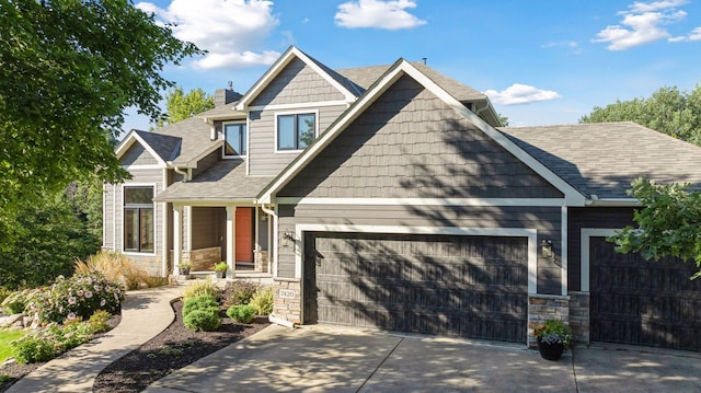 craftsman inspired home with concrete driveway, an attached garage, stone siding, and roof with shingles