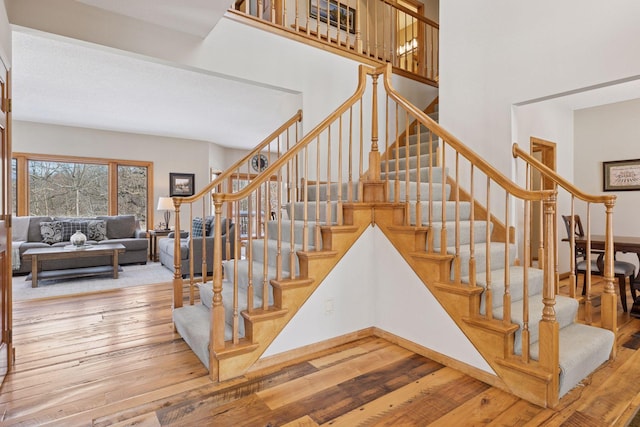 stairs featuring a high ceiling, baseboards, and wood-type flooring