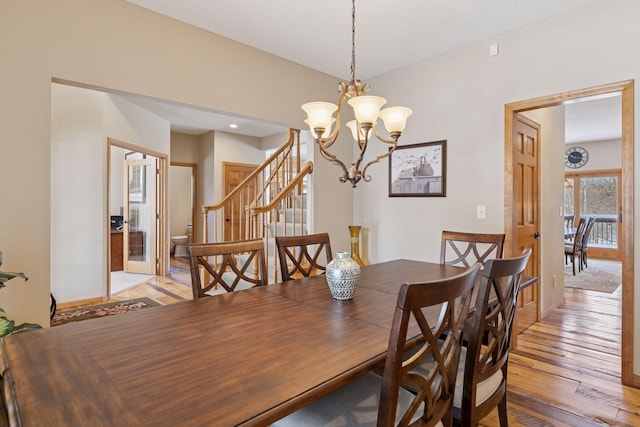 dining area featuring a notable chandelier, light wood-style floors, and stairs