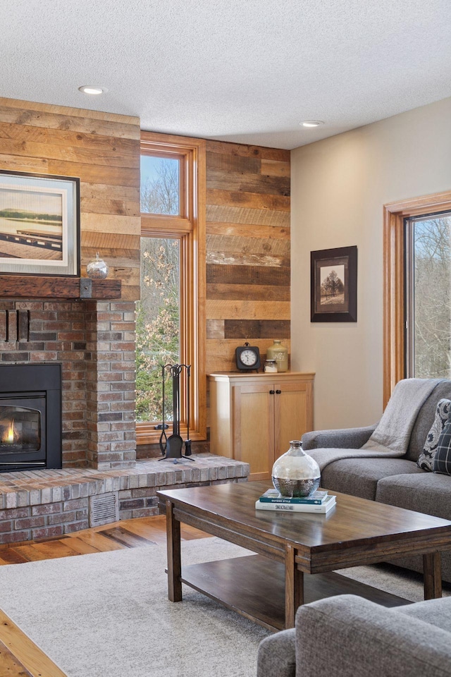 living area featuring plenty of natural light, a fireplace, a textured ceiling, and wood finished floors