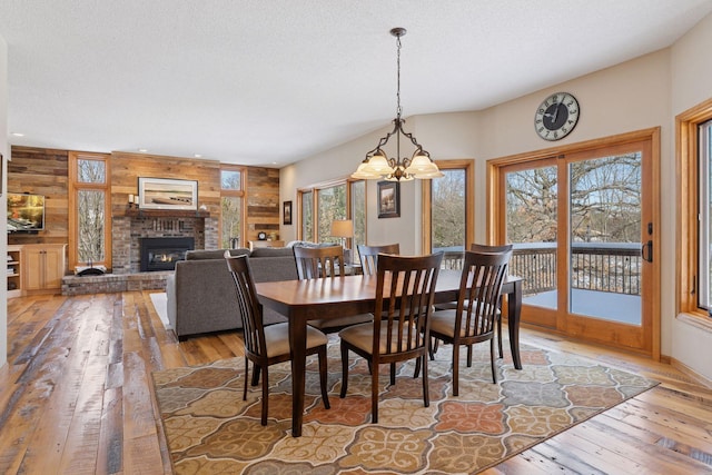 dining area with a wealth of natural light, a brick fireplace, a textured ceiling, and light wood-type flooring