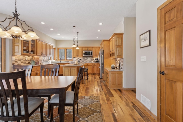 dining space with a textured ceiling, recessed lighting, visible vents, and light wood-type flooring