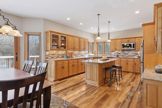 kitchen with stainless steel appliances, a healthy amount of sunlight, light wood-style flooring, and a center island