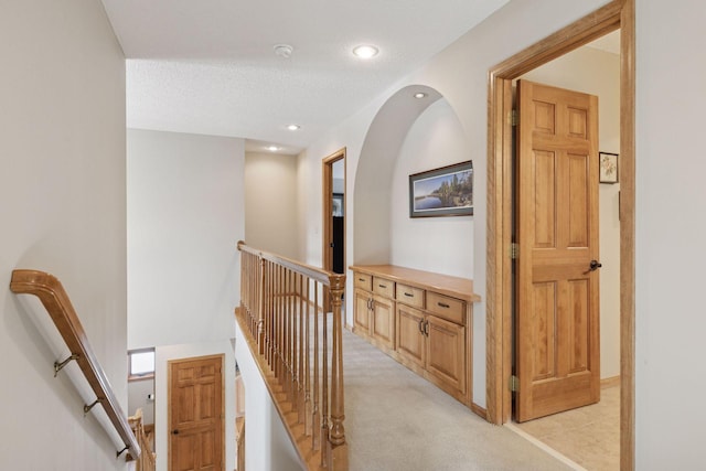 corridor with a textured ceiling, recessed lighting, an upstairs landing, and light carpet