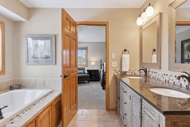 ensuite bathroom featuring a sink, tasteful backsplash, double vanity, and ensuite bathroom