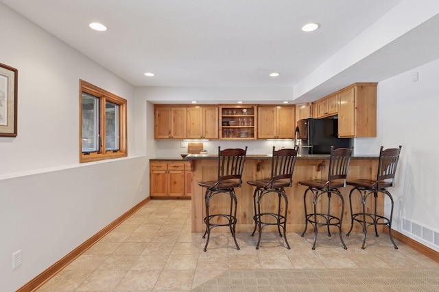 kitchen featuring visible vents, open shelves, freestanding refrigerator, a peninsula, and baseboards