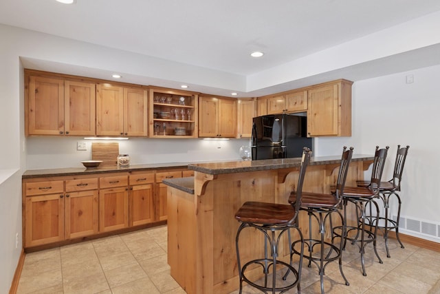 kitchen featuring a kitchen bar, open shelves, freestanding refrigerator, recessed lighting, and a peninsula