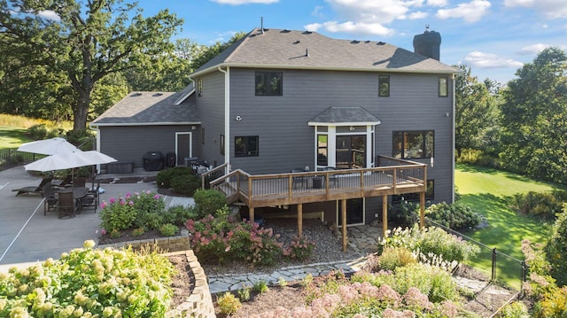 back of house with a shingled roof, fence, a chimney, a deck, and a patio