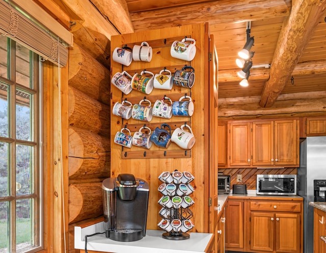 kitchen featuring appliances with stainless steel finishes, rail lighting, log walls, wood ceiling, and beam ceiling