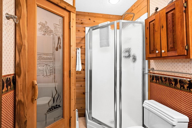 bathroom featuring toilet, a shower with door, and wood walls