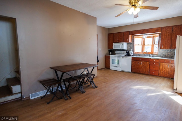 kitchen featuring white appliances, tasteful backsplash, brown cabinetry, and light countertops