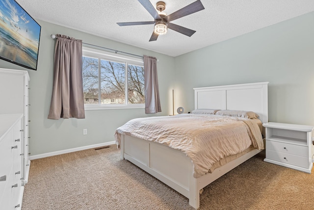 bedroom with baseboards, visible vents, light colored carpet, ceiling fan, and a textured ceiling