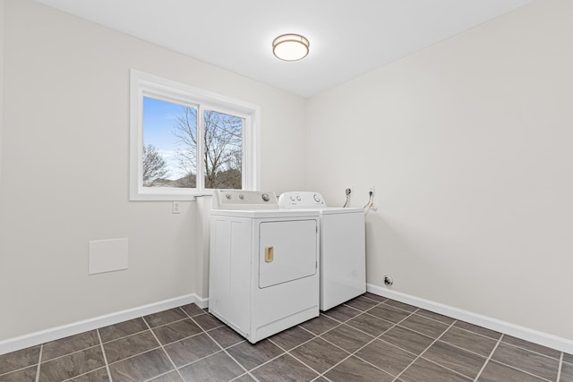 clothes washing area with laundry area, independent washer and dryer, dark tile patterned floors, and baseboards