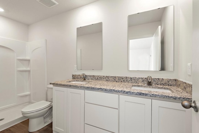 full bathroom with double vanity, toilet, visible vents, and a sink