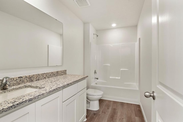 bathroom with visible vents, toilet, wood finished floors,  shower combination, and vanity