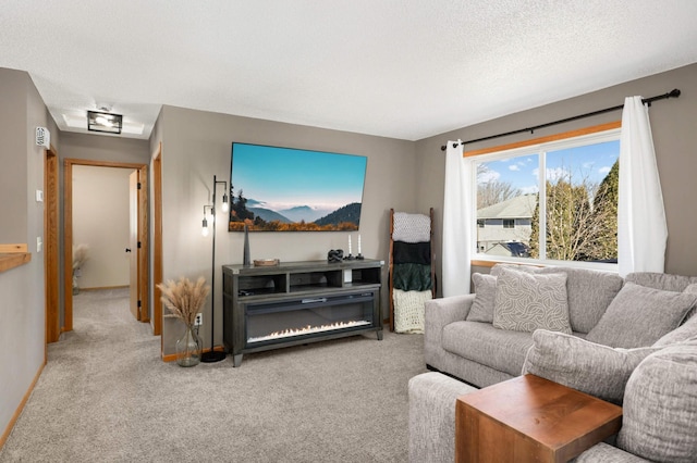 living room with carpet, attic access, a textured ceiling, and a glass covered fireplace