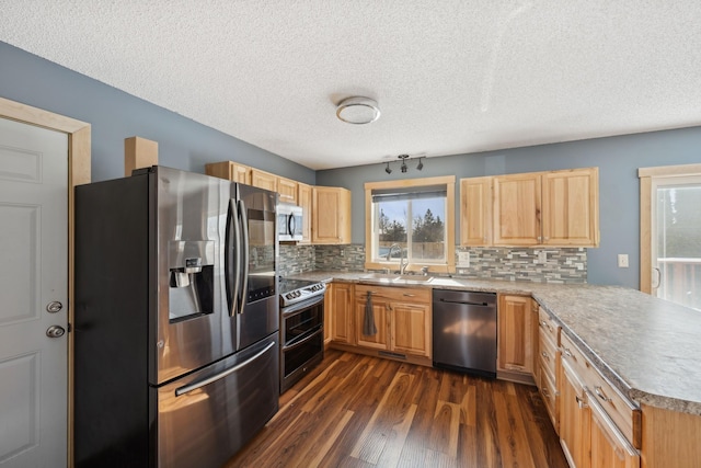 kitchen with a peninsula, dark wood-type flooring, a sink, light countertops, and appliances with stainless steel finishes