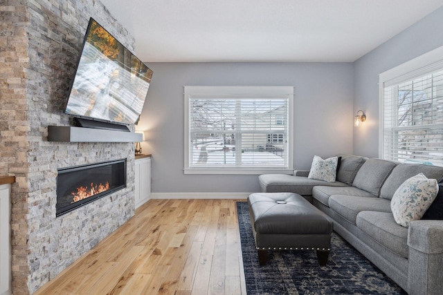 living room with light hardwood / wood-style flooring and a stone fireplace