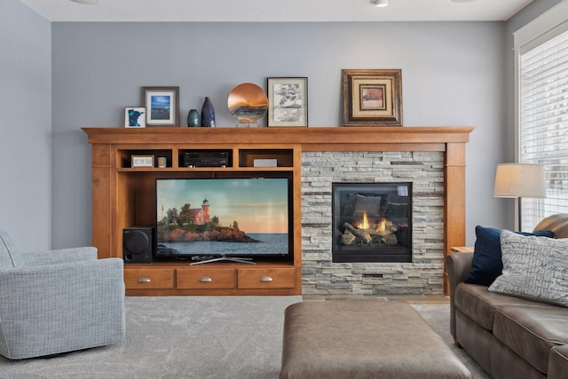 carpeted living room featuring a stone fireplace