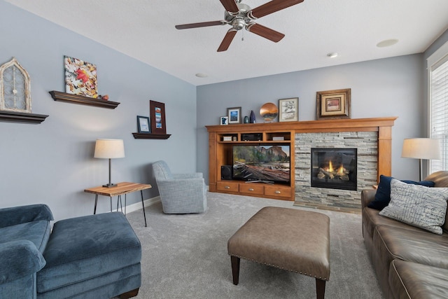 living room featuring carpet, ceiling fan, and a stone fireplace