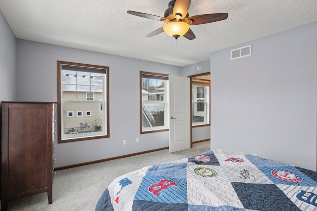 bedroom featuring a textured ceiling, ceiling fan, and light colored carpet