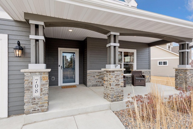 view of exterior entry featuring a porch and stone siding