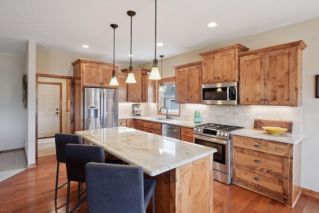 kitchen featuring a kitchen island, tasteful backsplash, appliances with stainless steel finishes, and a sink