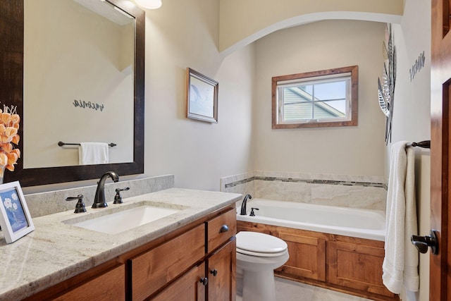 bathroom with a garden tub, vanity, and toilet