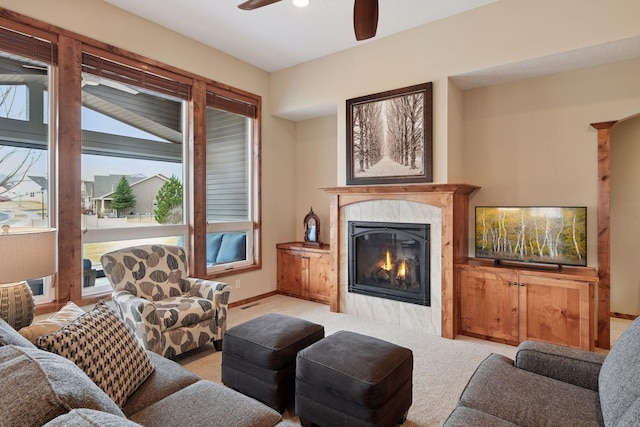 living room featuring light colored carpet, a ceiling fan, baseboards, and a premium fireplace