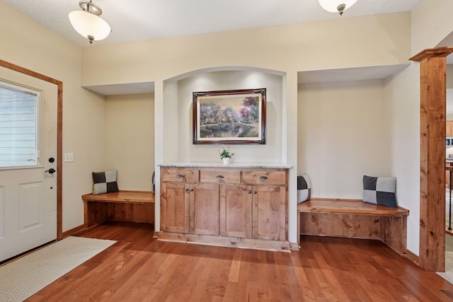 foyer entrance featuring baseboards, hardwood / wood-style floors, and ornate columns