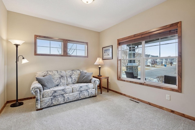 living area with baseboards, visible vents, and carpet floors